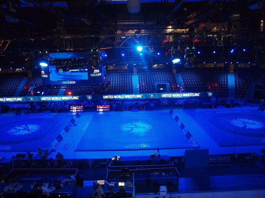Salle des championnats du monde de lutte 2021 à Oslo, tapis éclairés en bleu sous les bannières United World Wrestling