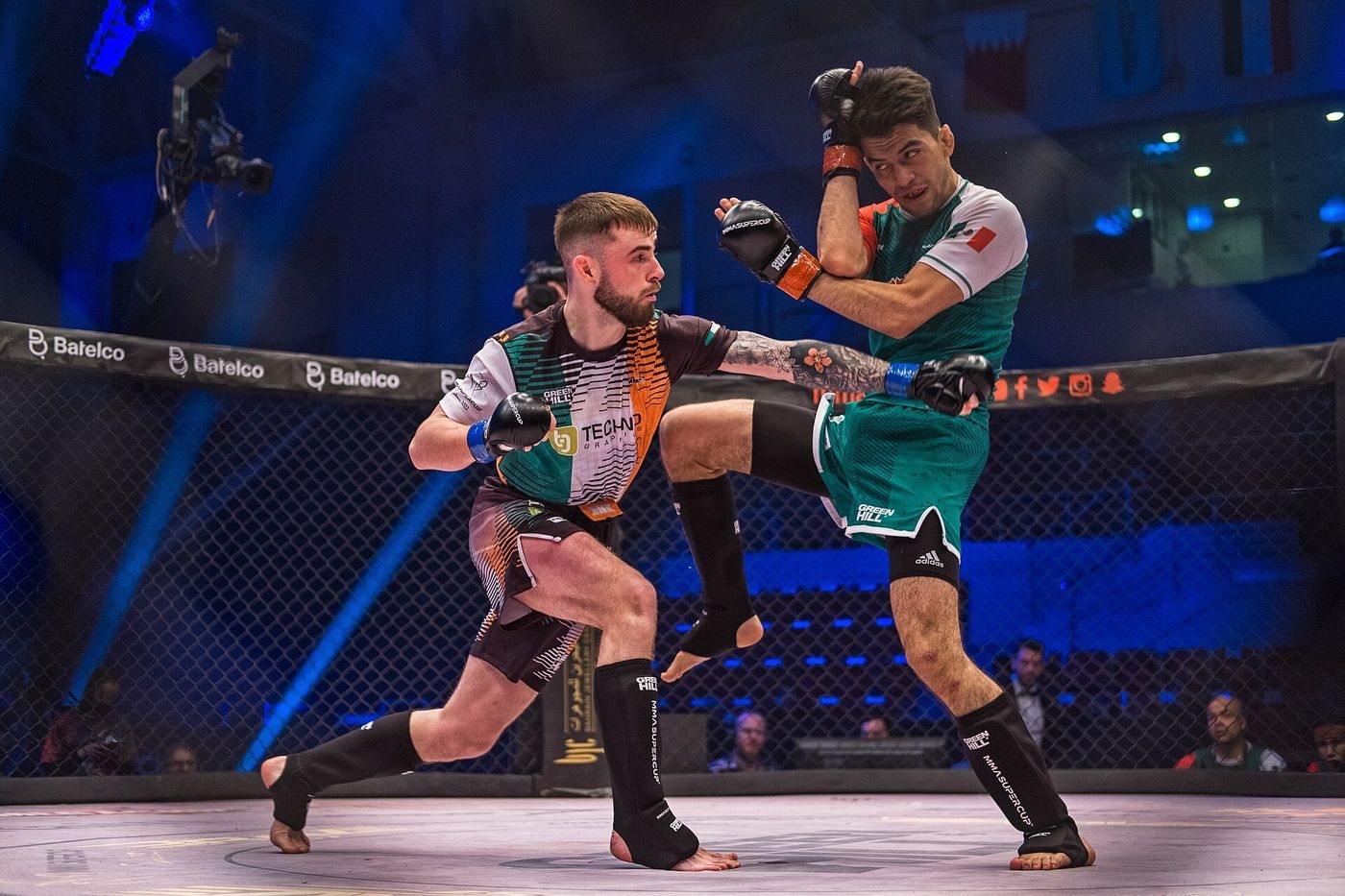 Combattant mexicain portant un coup de pied sautant à son adversaire irlandais dans la cage, aux championnats du monde IMMAF de MMA amateur à Bahreïn