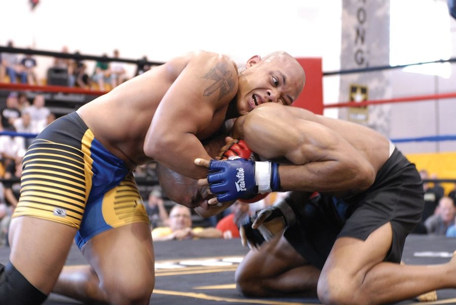 Deux combattants en corps-à-corps au sol, l'un contrôlant la tête de l'autre, lors d'un championnat de MMA à Fort Benning